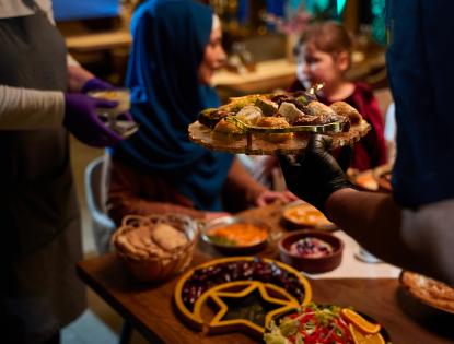 In a heartwarming scene a professional chef serves Mediterranean cuisine to a table of male and female guests 